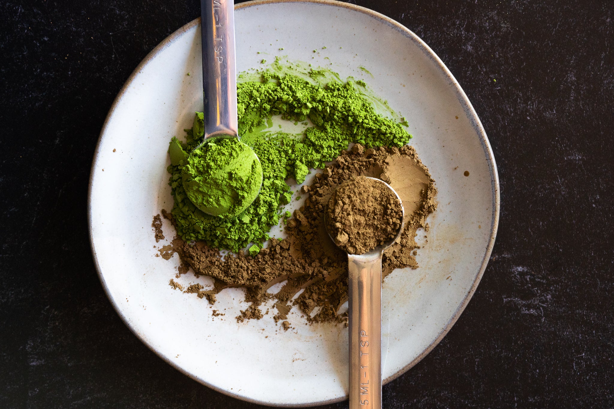 Matcha and Hojicha powder mixed on a plate with tea spoons